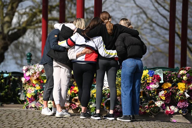 A group of women hug as they stand in front of tributes for Sarah Everard 