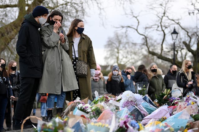 A woman reacts as she looks at tributes