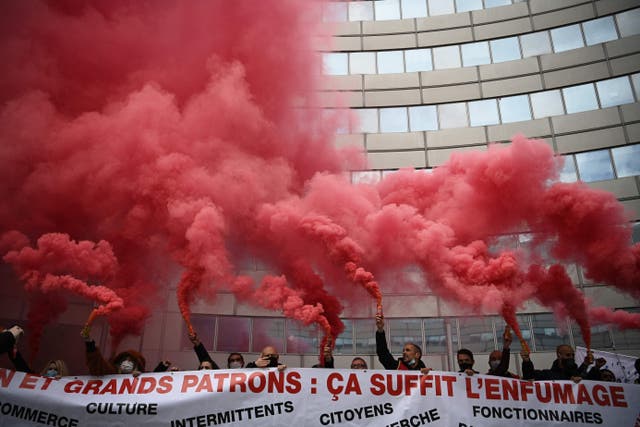 Protesters hold a banner and burning red flares during a demonstration of called by unions of healthcare and social workers in support of their sector and to demand a bonus in their pay in Paris