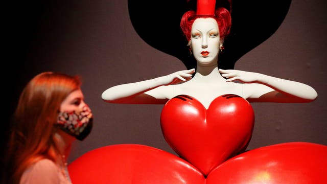 An employee stands before a costume for the Queen of Hearts by Bob Crowley on display at the Alice: Curiouser and Curiouser exhibition at the Victoria and Albert Museum in London