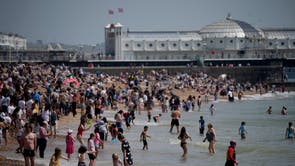 ブライトンビーチで暑い日を楽しんでいる人々は、海に足を踏み入れます