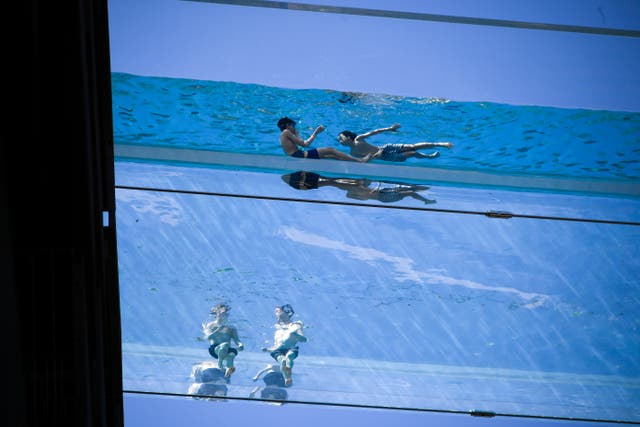 Mense swem in die Sky Pool, 'n deursigtige swembadbrug oor twee eksklusiewe woonblokke wat langs die Amerikaanse ambassade in Nine Elms staan, in Londen, Dinsdag, Junie 1, 2021