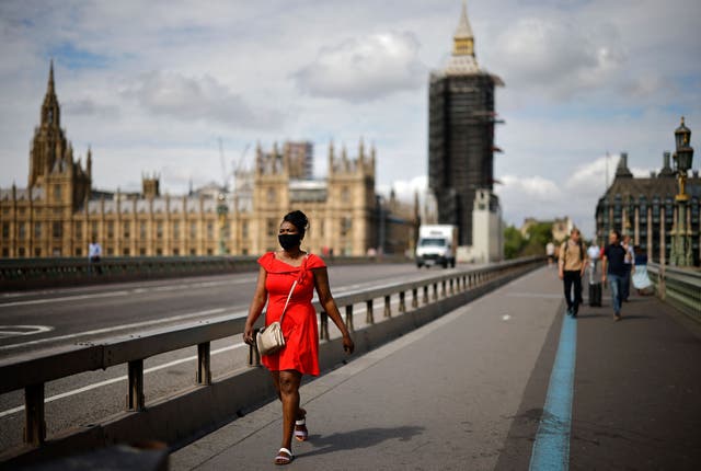 'N Voetganger met 'n gesigbedekking loop oor Westminster Bridge naby die Houses of Parliament in Londen
