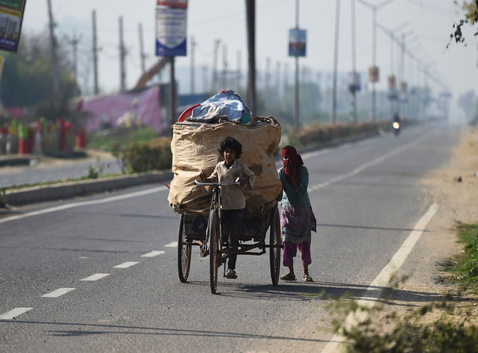 <p>A child pulls a garbage cycle rickshaw as his mother pushes it along a street during Covid-19 curfew in Haryana on 22 行進, 2020.<pp>