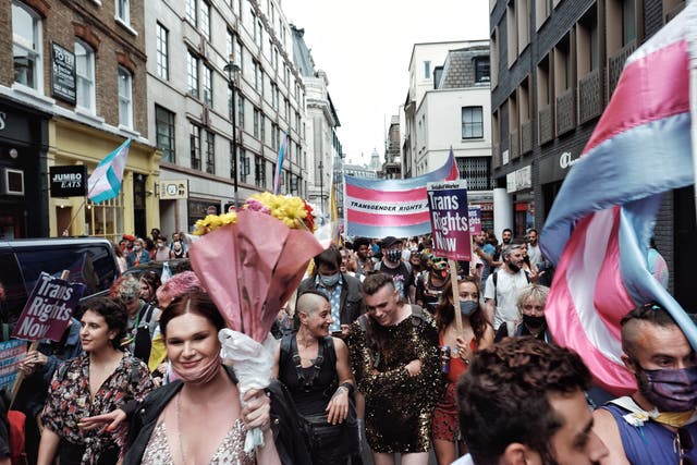 'N Paar optoggangers in 'n Trans Pride-saamtrek deel 'n glimlag in Soho