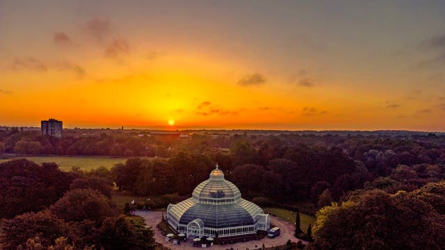 The sun rises behind the Sefton Park Palm House, in Sefton Park, Liverpool