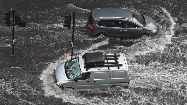 Vehicles drive through deep water on a flooded road in Nine Elms, 伦敦