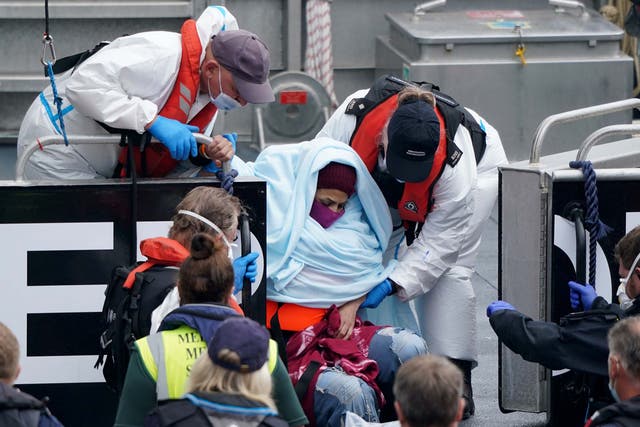 A woman is helped by Border Force officers as a group of people thought to be migrants are brought in to Dover, Kent, onboard a Border Force vessel, following a small boat incident in the Channel