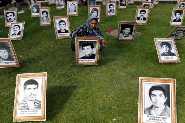 在伊朗全国抵抗委员会支持者组织的示威活动中，一名抗议者在一张被处决的男子的照片上献花 (NCRI) 抗议伊朗新总统易卜拉欣·赖西在伦敦市中心的就职典礼