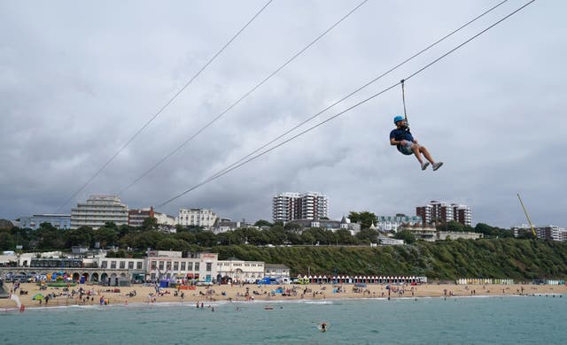 People zip wire across the sea from Bournemouth pier towards the beach.