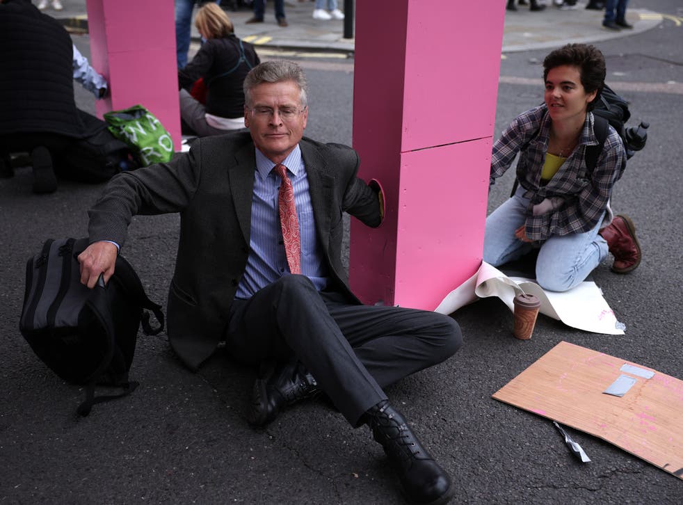 <p>Protestors lock their arms into the giant pink table to stop police from removing it </p>