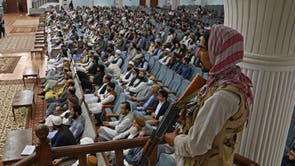 A Taliban fighter stands guard as Talibans acting Higher Education Minister Abdul Baqi Haqqani (not pictured) addresses a gathering during a consultative meeting on Taliban's general higher education policies at the Loya Jirga Hall in Kabu