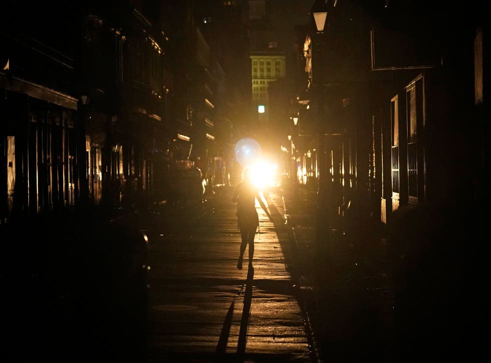 <p>A police officer patrols past woman walking along Bourbon Street</磷>