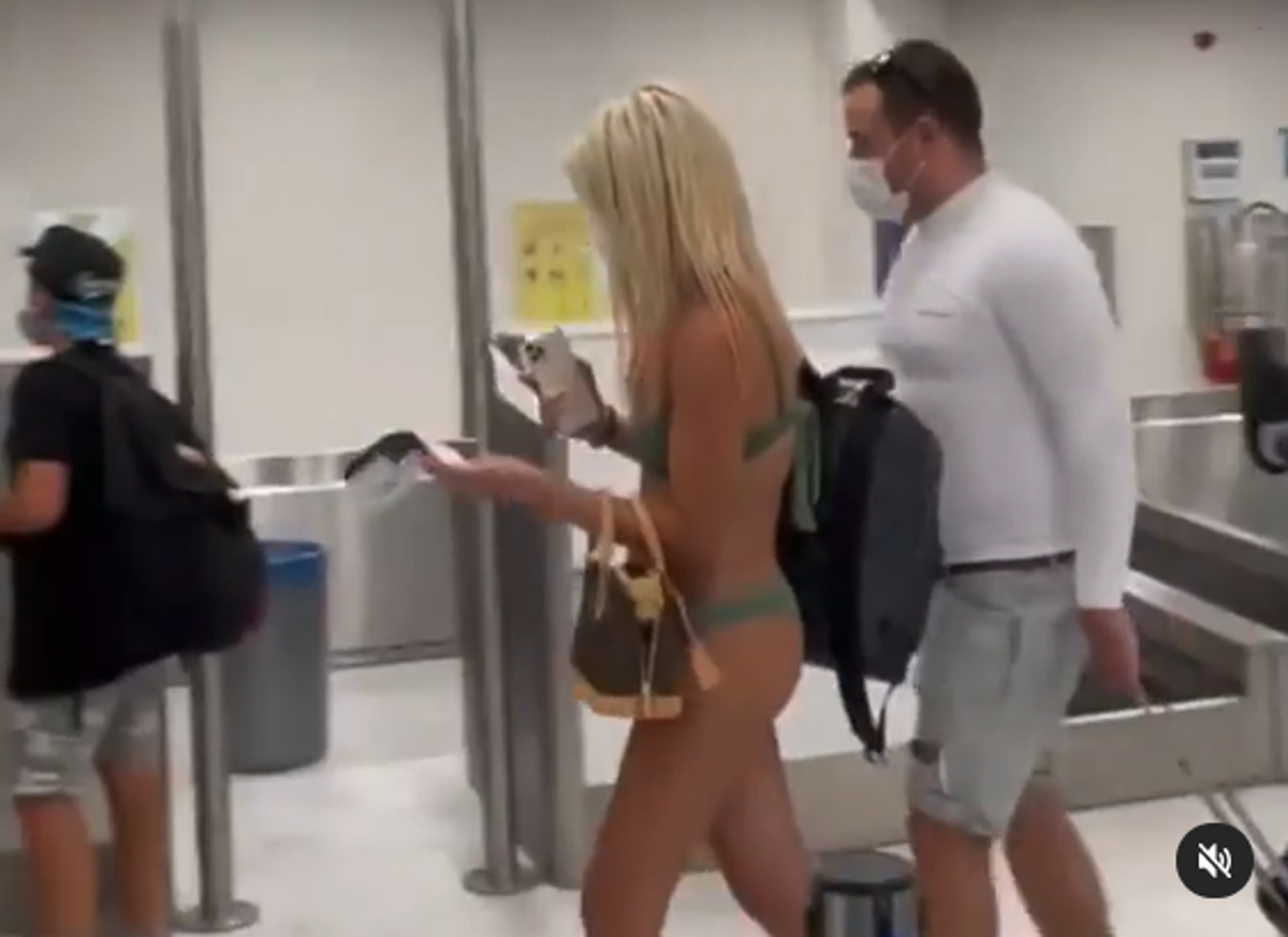Woman strolls through airport wearing just a bikini – and face mask