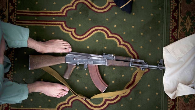 A Taliban fighter lays his AK-47 rifle down during Friday prayers at a Mosque in Kabul, 阿富汗