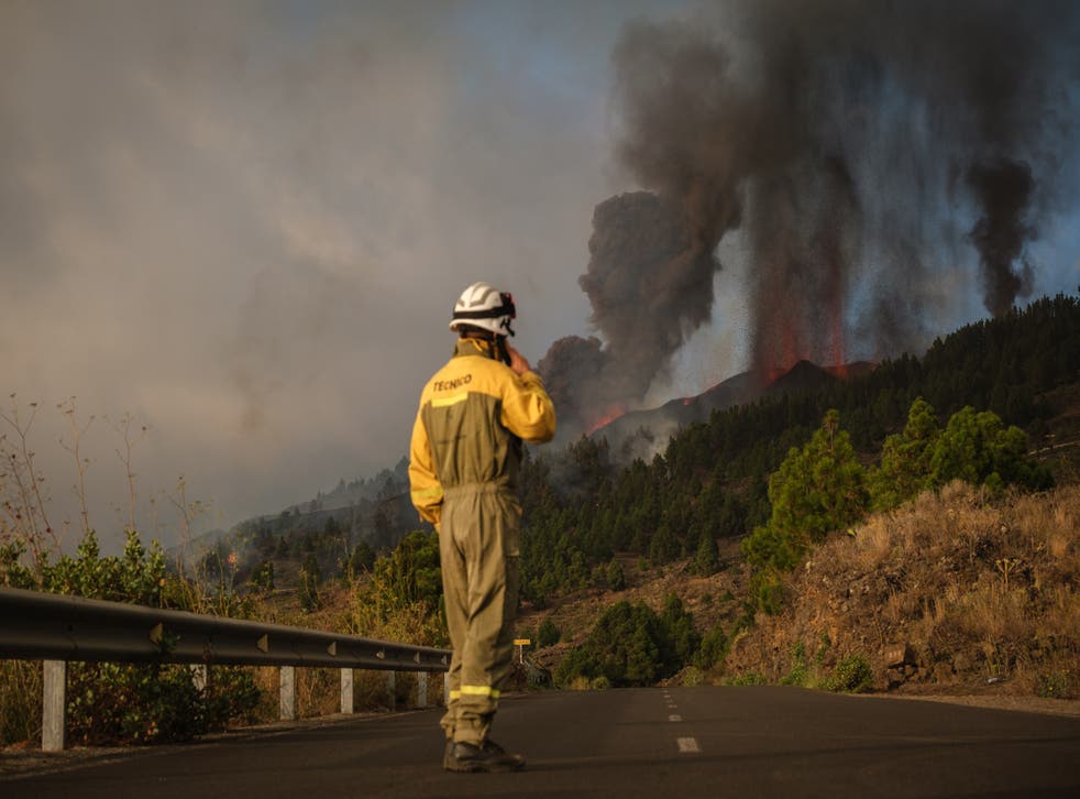 <p>Firefighters at the scene as smoke billows from the volcano</s>