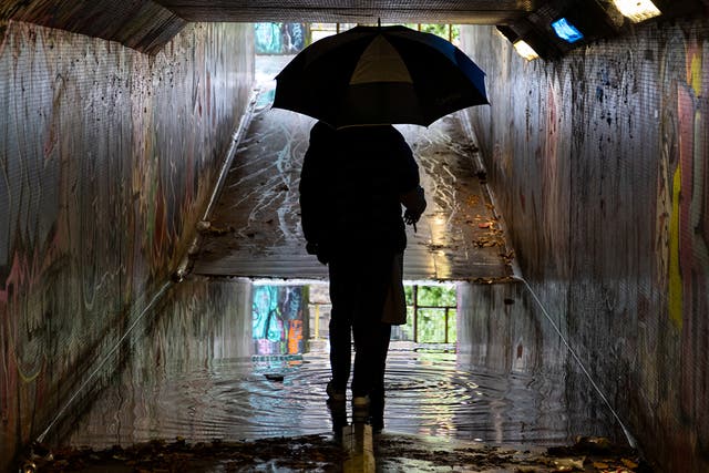 一对夫妇穿过布里斯托尔一条被水淹的地下通道，英国部分地区发布了黄色的雨和风天气警告
