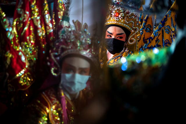 バンコクで毎年恒例の菜食主義の祭りの間に神社で演奏する前に、保護マスクを身に着けている中国のオペラ団のメンバーが準備します, タイ