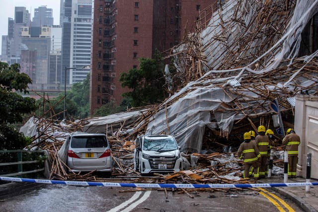 Rescue personnel at the scene where bamboo scaffolding by a high-rise residential building collapsed onto a road, following strong winds and heavy rain from weather patterns from a tropical storm, in Hong Kong