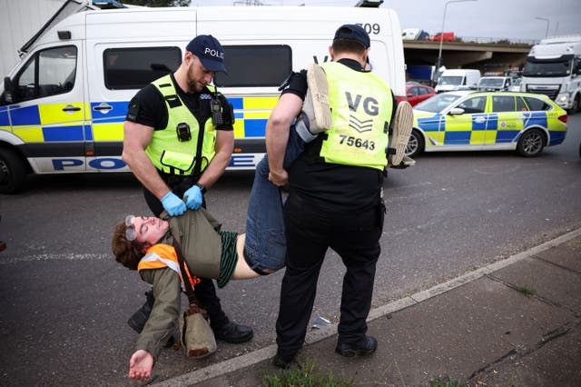 Polisiebeamptes hou 'n man aan terwyl Insulate Britain-aktiviste 'n rotonde by 'n aansluiting op die M25-snelweg blokkeer tydens 'n betoging in Thurrock