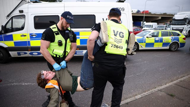 Des policiers arrêtent un homme alors que des militants d'Isulate Britain bloquent un rond-point à un carrefour de l'autoroute M25 lors d'une manifestation à Thurrock