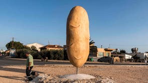 A man walks past a sculpture of a giant potato in the village of Xylofagou, which is renowned for its potato production, in southeastern Cyprus