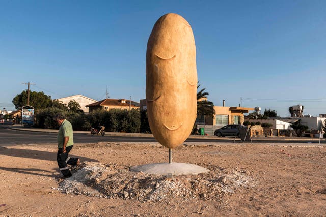 Xylofagouの村で巨大なジャガイモの彫刻を通り過ぎる男, ジャガイモの生産で有名です, キプロス南東部