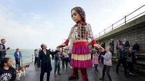 演员裘德·洛与小阿迈勒牵手, 一个 3.5 米高的叙利亚九岁女孩的木偶, 当它到达福克斯通时, 肯特, 作为 Handspring Puppet Company 的“The Walk”的一部分