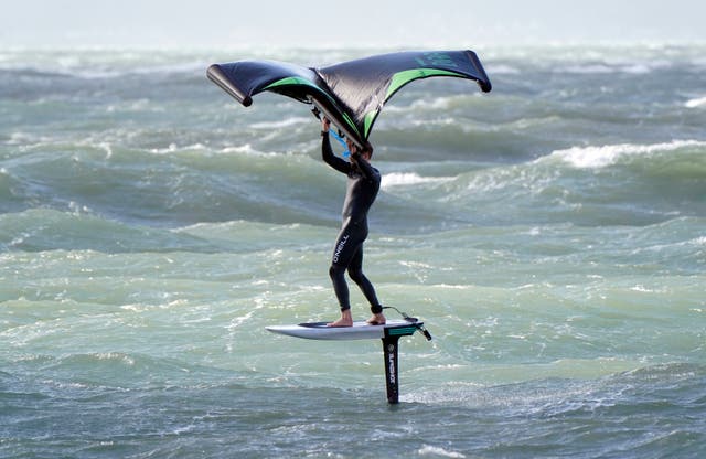 A wing surfer enjoys the strong winds as they surf in the sea off of Hayling Island in Hampshire