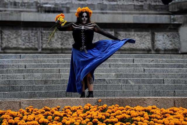 Une femme déguisée en Catrina est représentée à côté de décorations avec Cempazuchitl -Mexican Marigold (Tagetes erecta)- situé le long de l'avenue Paseo de la Reforma dans le cadre des préparatifs de la célébration du Jour des Morts, à Mexico