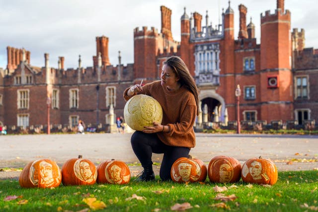 Palace Gardener Justine Howlett adds the finishing touches to pumpkins bearing the face of Henry VIII and his wives, at Hampton Court Palace. 