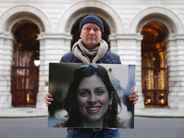 リチャード・ラットクリフは、ハンガーストライキ中に外務省の外で抗議している妻のナザニン・ザガリ・ラトクリフの写真を掲げています。, 英国の外務大臣に、妻をイランでの拘禁から家に連れて帰るよう働きかける努力の一環