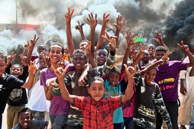 Sudanesiske ungdommer viser seierstegn ved en veisperring laget av brennende dekk i hovedstaden Khartoum mens de protesterer mot et militærkupp som styrtet overgangen til sivilt styre