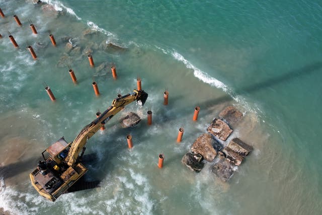 Des travailleurs utilisent un bulldozer au large de la plage de la ville de Gaza pour installer des échasses dans la mer Méditerranée afin de construire un café