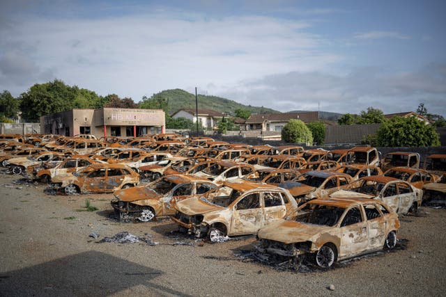 車の残骸は、マンジニでの7月の騒乱の間に抗議者によって焼失したディーラーで見られます,