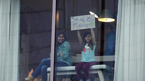 A young girl holds up a sign saying ‘save our planet’ at a hotel window overlooking the conference