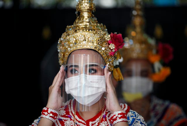 Un danseur ajuste un écran facial lors d'une représentation pour adorer Lord Brahma, le dieu hindou de la création, au lieu touristique presque vide du sanctuaire d'Erawan à Bangkok, Thaïlande