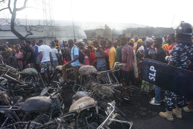 People look on at a pile of burnt motorbikes in the aftermath of a fuel tanker explosion in Freetown