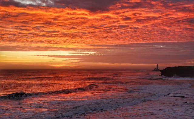 イングランド北東海岸のホイットリーベイにあるセントメアリーズ灯台から昇る朝日
