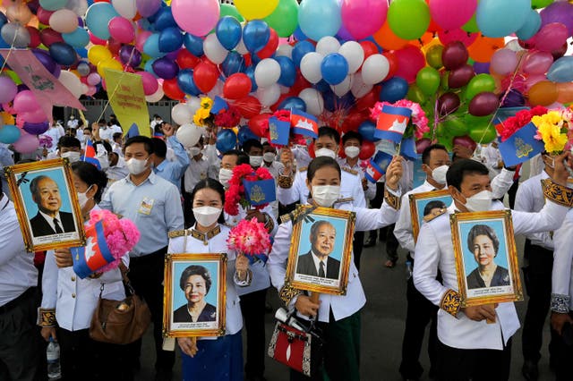 Les gens tiennent des portraits de l'ancien roi Norodom Sihanouk et de l'ancienne reine Monique au monument de l'indépendance lors d'une cérémonie marquant le jour de l'indépendance du Cambodge à Phnom Penh