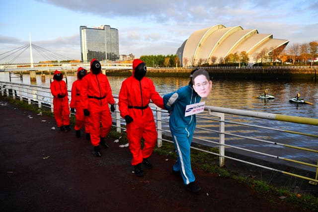 Klimaataktiviste aangetrek as karakters geïnspireer deur die Netflix-reeks "Squid Game" protesteer terwyl hulle Samsung vra om te gaan 100% hernubare energie, buite die lokaal vir COP26 in Glasgow