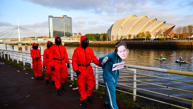 Des militants pour le climat déguisés en personnages inspirés de la série Netflix "Squid Game" manifestent alors qu'ils demandent à Samsung de partir 100% énergie renouvelable, à l'extérieur du lieu de la COP26 à Glasgow