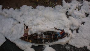 ヤムナ川で男がボートを漕ぐ, 産業および家庭の汚染によって引き起こされた化学泡で覆われている, ニューデリーのChhathPujaフェスティバル中