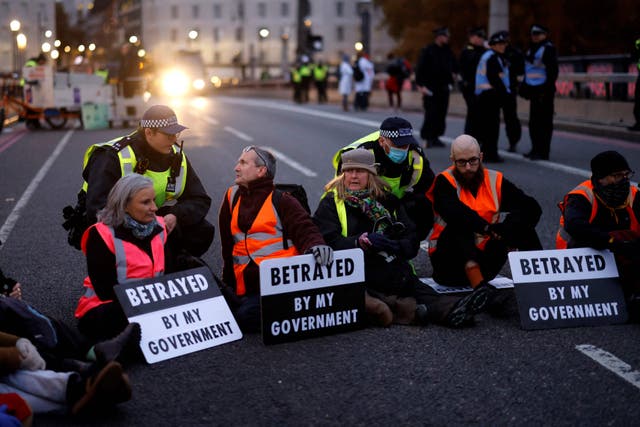 Policiais monitoram ativistas da mudança climática sentados e bloqueando o trânsito durante uma ação de protesto em solidariedade aos ativistas do grupo Insulate Britain, que receberam penas de prisão por bloquearem estradas, na Lambeth Bridge, no centro de Londres 