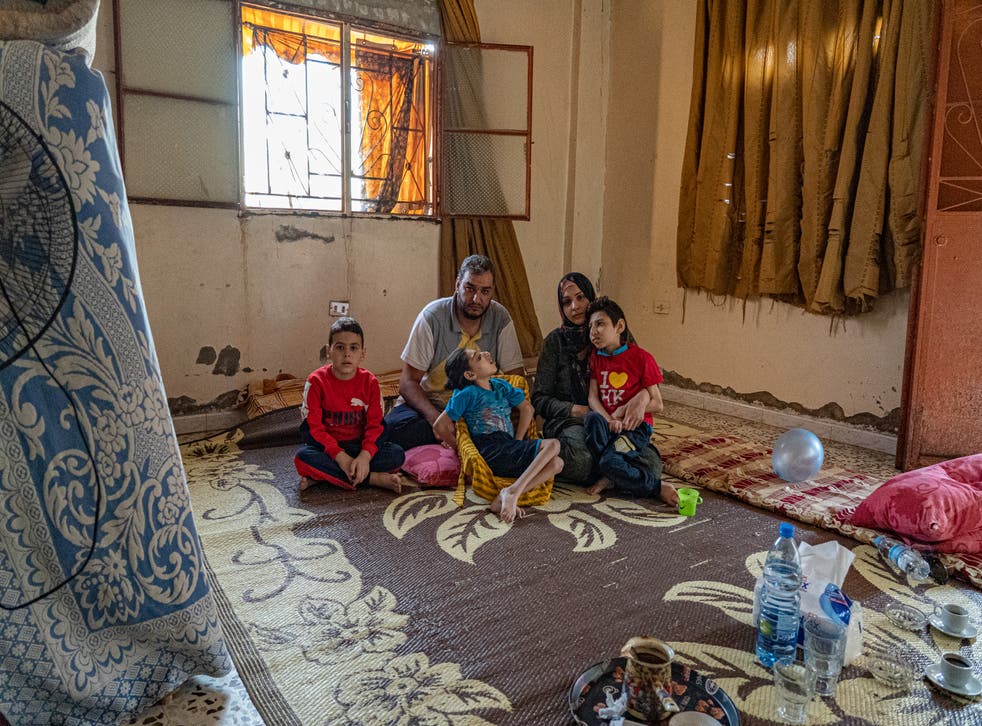 <p>Hanan and her family sit on the floor of one of two rooms they live in</p>