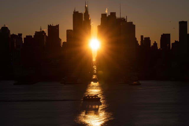 ニューヨークの逆「マンハッタンヘンジ」の最中に、42丁目から昇る朝日, ウィホーケンから撮影したニューヨーク, ニュージャージー. 「マンハッタンヘンジ」は、マンハッタンのメインストリートグリッドの東西の通りに夕日または昇る太陽が揃う現象です。, ニューヨーク市. 