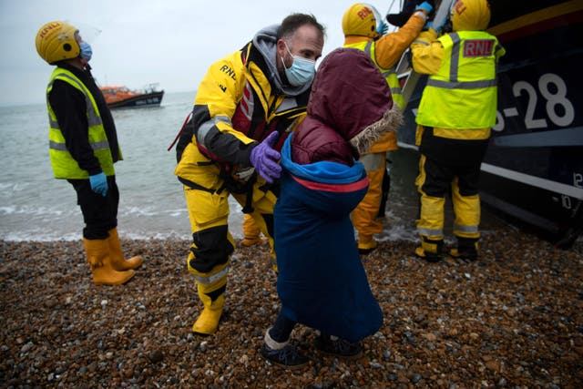 Migrants are helped ashore from a RNLI (Royal National Lifeboat Institution) lifeboat at a beach in Dungeness, on the south-east coast of England, on November 24, 2021, after being rescued while crossing the English Channel.