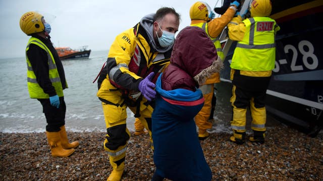 Migrants are helped ashore from a RNLI (Royal National Lifeboat Institution) lifeboat at a beach in Dungeness, on the south-east coast of England, 11月 24, 2021, after being rescued while crossing the English Channel.