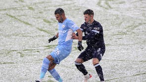 Riyad Mahrez of Manchester City battles for possession with Aaron Cresswell of West Ham United during a match at the Etihad during snow