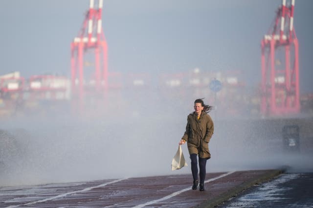 Une personne essaie d'éviter les embruns sur la promenade de New Brighton à Wallasey alors que le Royaume-Uni se prépare à l'arrivée de la tempête Barra